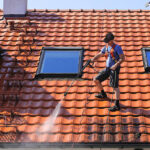 Worker is cleaning the roof and rainwater gutter with high pressure.